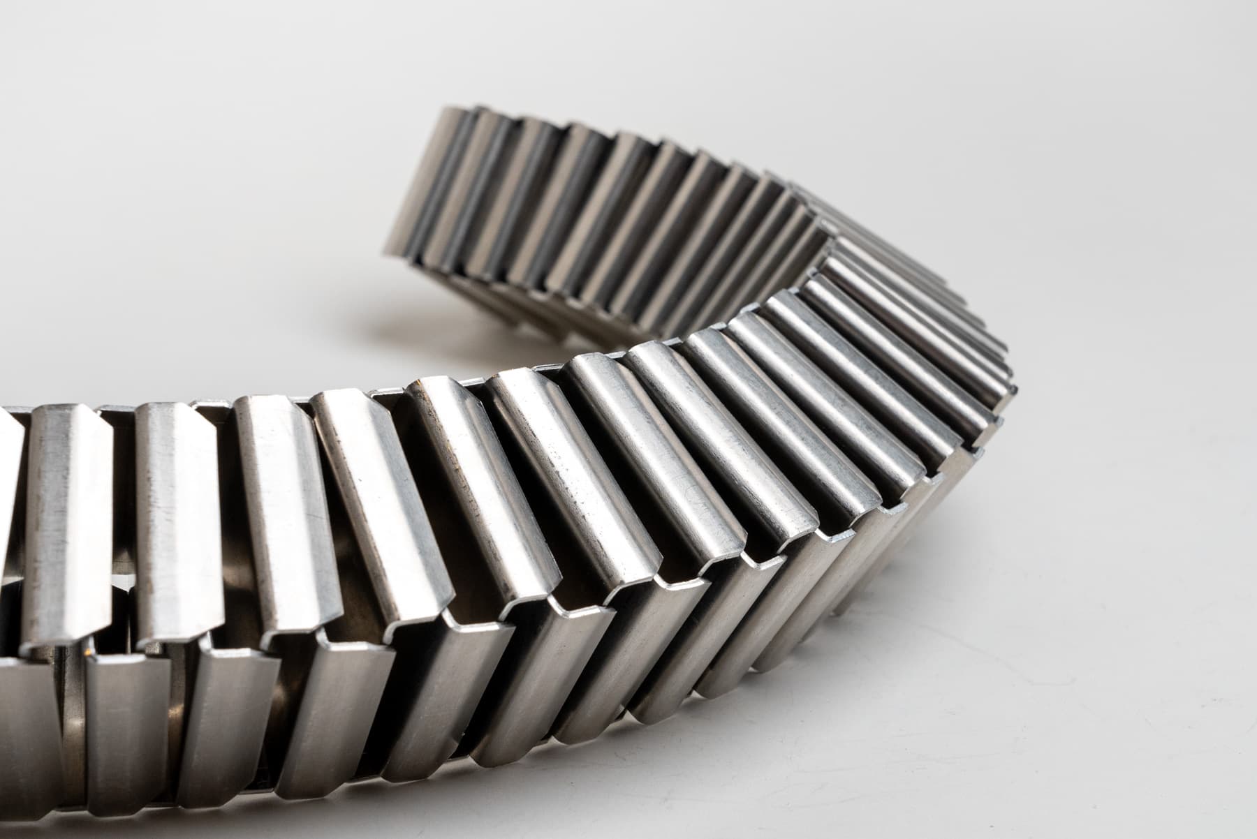 A long string of modular C-shaped clips made from aluminum sheets, each clipping onto the next in an alternating sequence.
